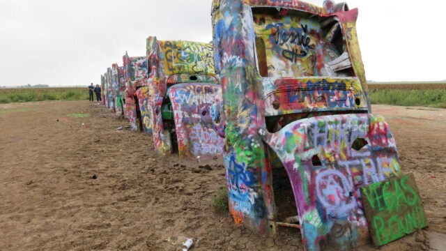 Rad farebných Cadillacov v piesku | Zdroj: route66usa.sk Farebné autá značky Cadillac zakopané v piesku na Cadillac Ranch v Amarillo, Texas